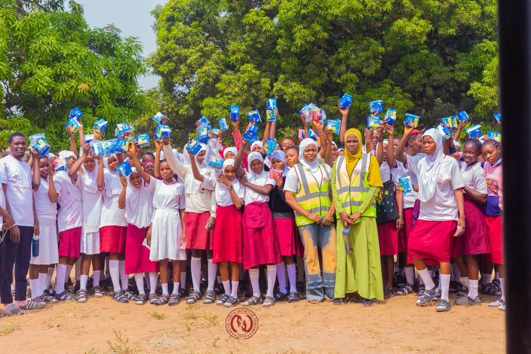 A large group of schoolgirls holding up donated sanitary pads